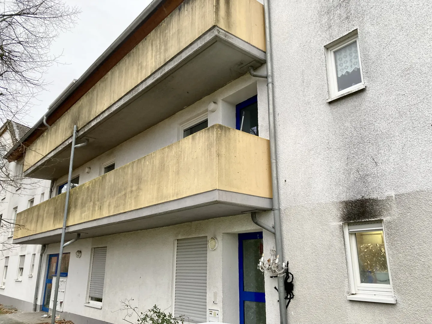 Társasházi erkélyes homlokzat sötétebb elszíneződésekkel a felületeken.